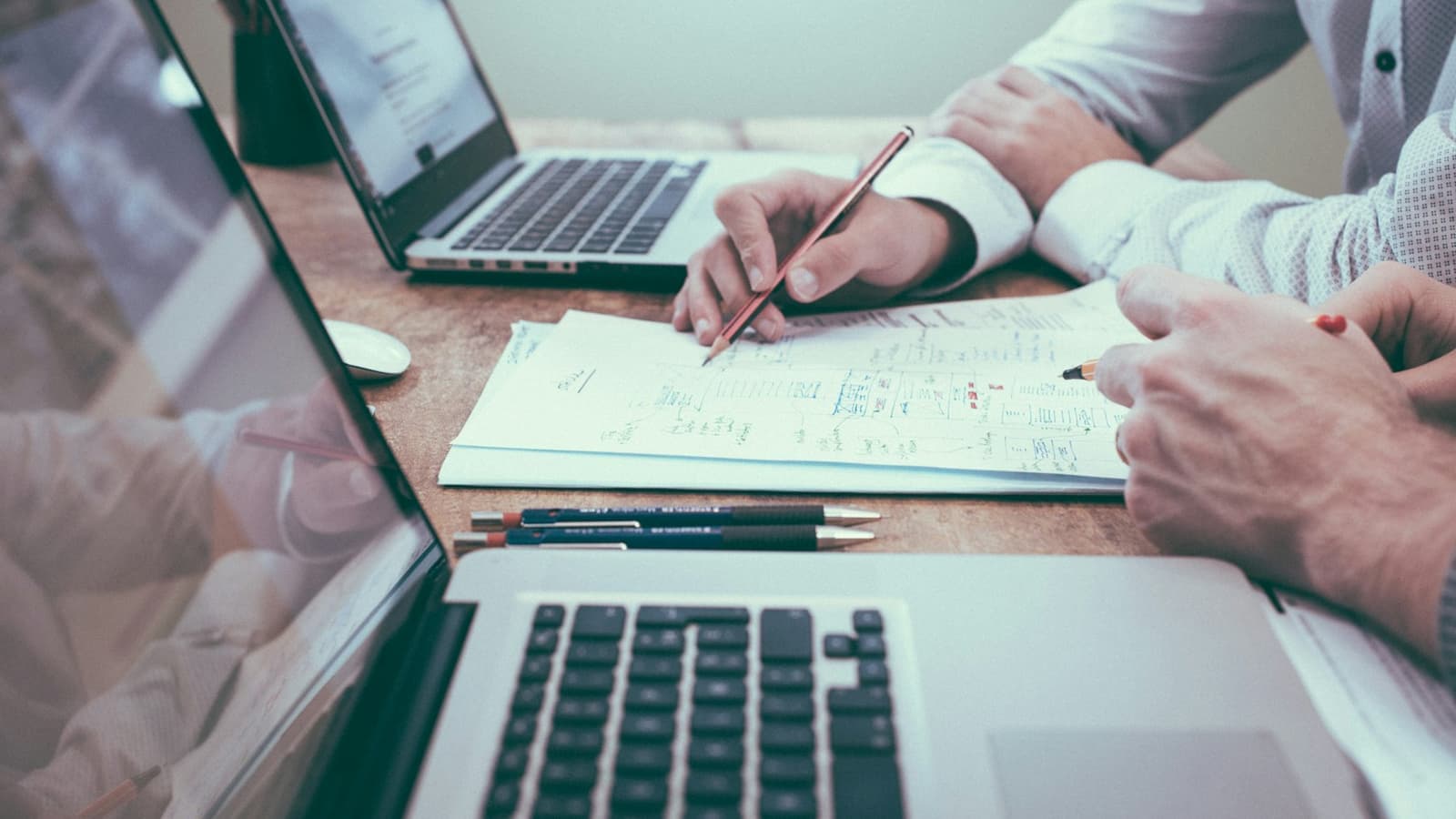 Two consultants working through a hand-drawn plan alongside laptops.