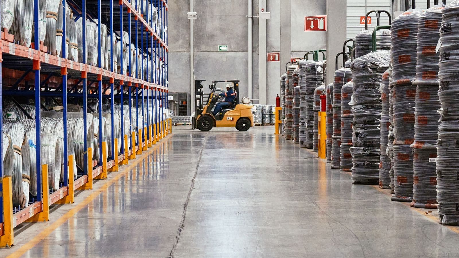 A forklift working a warehouse aisle racked with coiled cable and industrial stock.